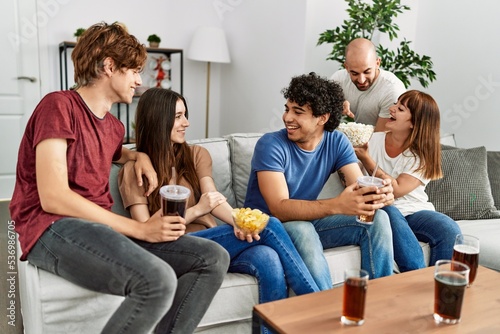 Group of young friends having party sitting on the sofa at home.