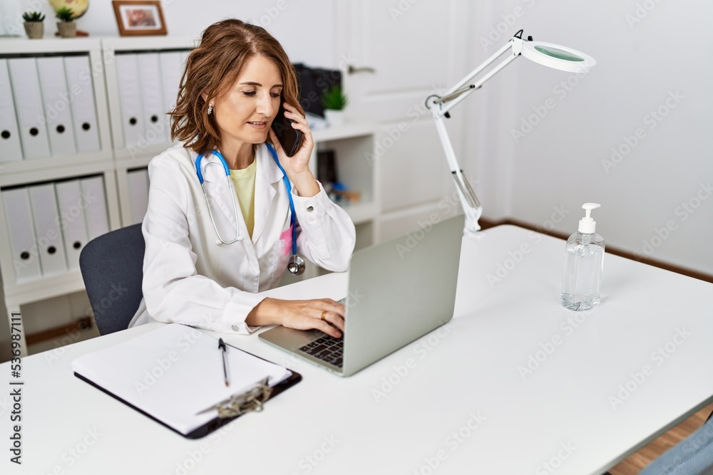 Middle age hispanic woman wearing doctor uniform talking on the smartphone at clinic Middle age hispanic woman wearing doctor uniform talking on the smartphone at clinic