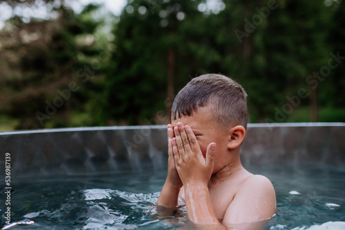 Little boy in outdoor hot tub. Summer holiday, vacation concept.