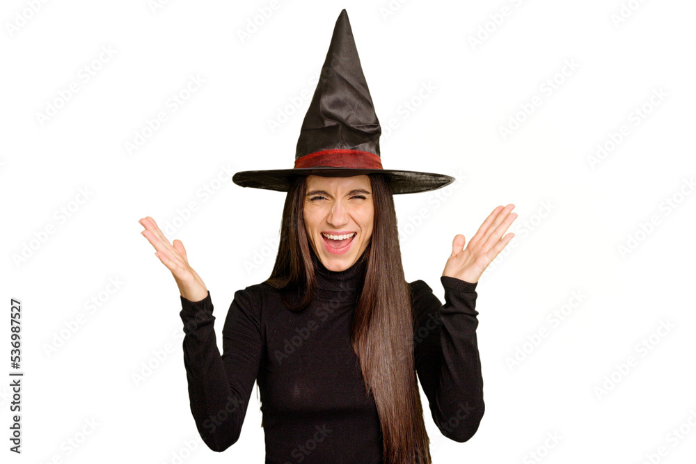 Young caucasian woman dressed as a witch for halloween day isolated receiving a pleasant surprise, excited and raising hands. Young caucasian woman dressed as a witch for halloween day isolated receiving a pleasant surprise, excited and raising hands.