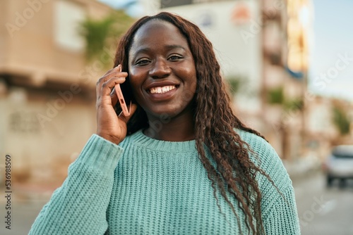 Young african woman smiling happy speaking on the phone at the city