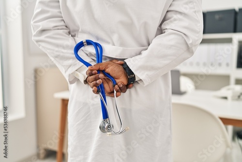 Young african american man wearing doctor uniform holding stethoscope at clinic