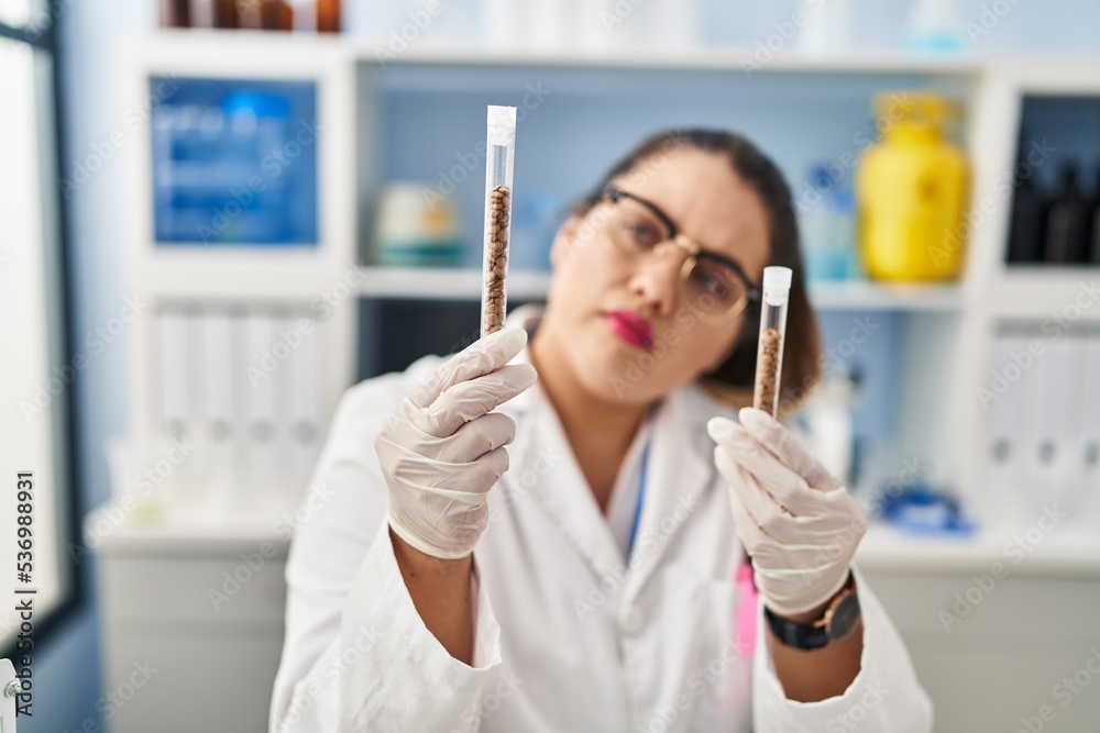Young beautiful plus size woman scientist holding test tubes at pharmacy