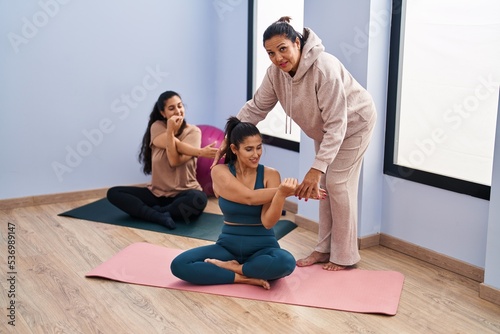 Three woman wearing sportswear stretching at sport center