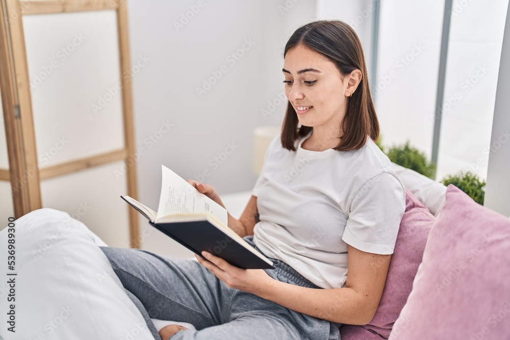 Young hispanic woman reading book sitting on bed at bedroom Young hispanic woman reading book sitting on bed at bedroom