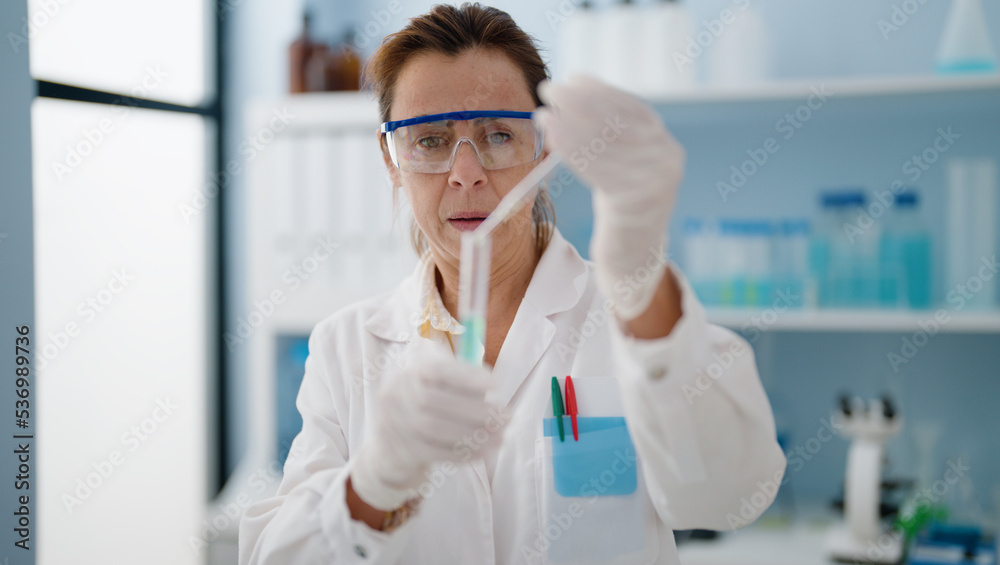 Middle age hispanic woman wearing scientist uniform working at laboratory