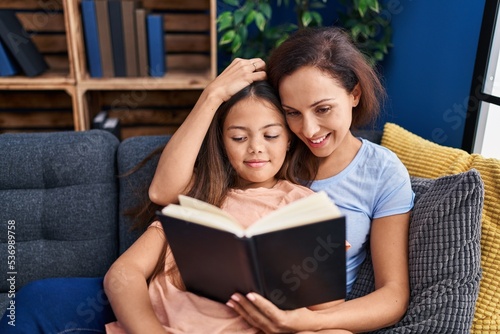Woman and girl mother and daughter reading book at home