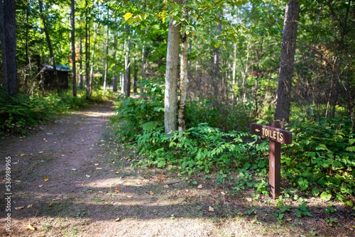 Canvas Print Brown toilets sign with an arrow by a path in the campground in Wisconsin