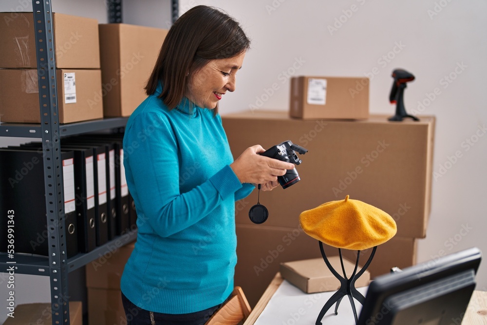 Middle age woman ecommerce business worker making photo to beret at office