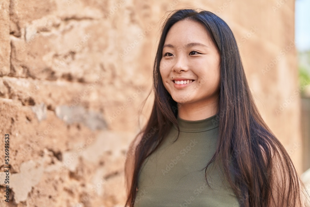 Young chinese woman smiling confident looking to the side at street