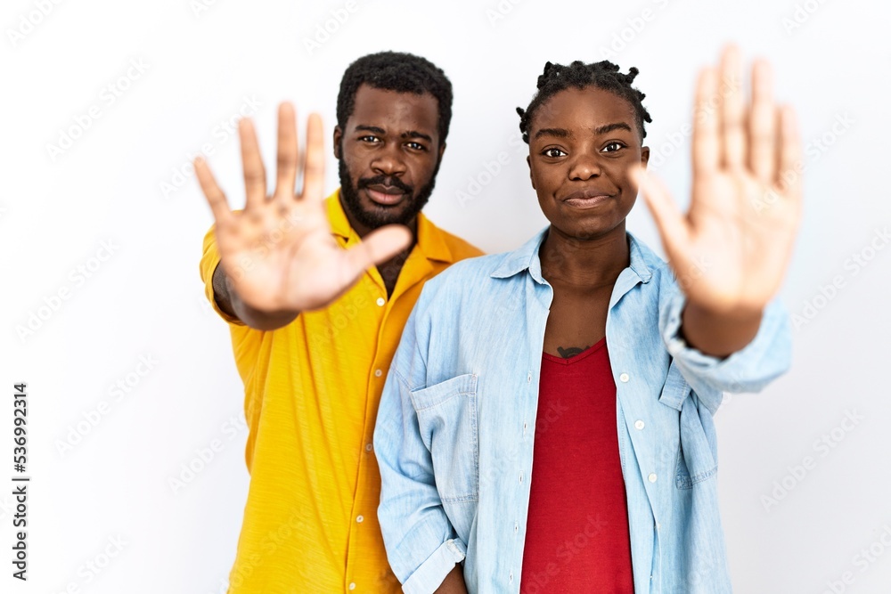 Young african american couple wearing casual clothes doing stop sing with palm of the hand. warning expression with negative and serious gesture on the face. Young african american couple wearing casual clothes doing stop sing with palm of the hand. warning expression with negative and serious gesture on the face.