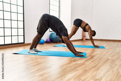 Young african american sporty couple training yoga at sport center.