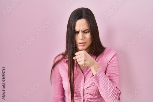 Young hispanic woman standing over pink background feeling unwell and coughing as symptom for cold or bronchitis. health care concept. © Krakenimages.com