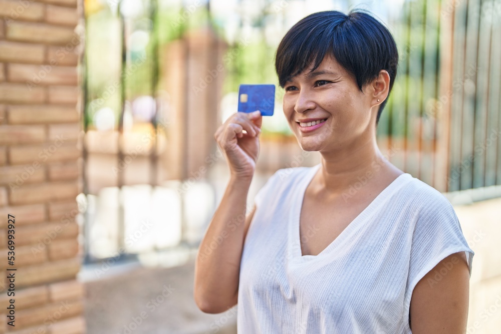 Middle age chinese woman smiling confident holding credit card at street Middle age chinese woman smiling confident holding credit card at street