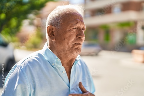 Senior grey-haired man standing suffering for heart attack at street