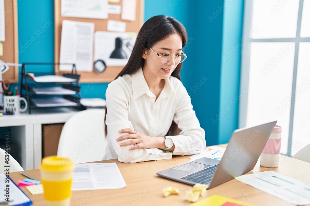 Young chinese woman business worker smiling confident sitting with arms crossed gesture at office