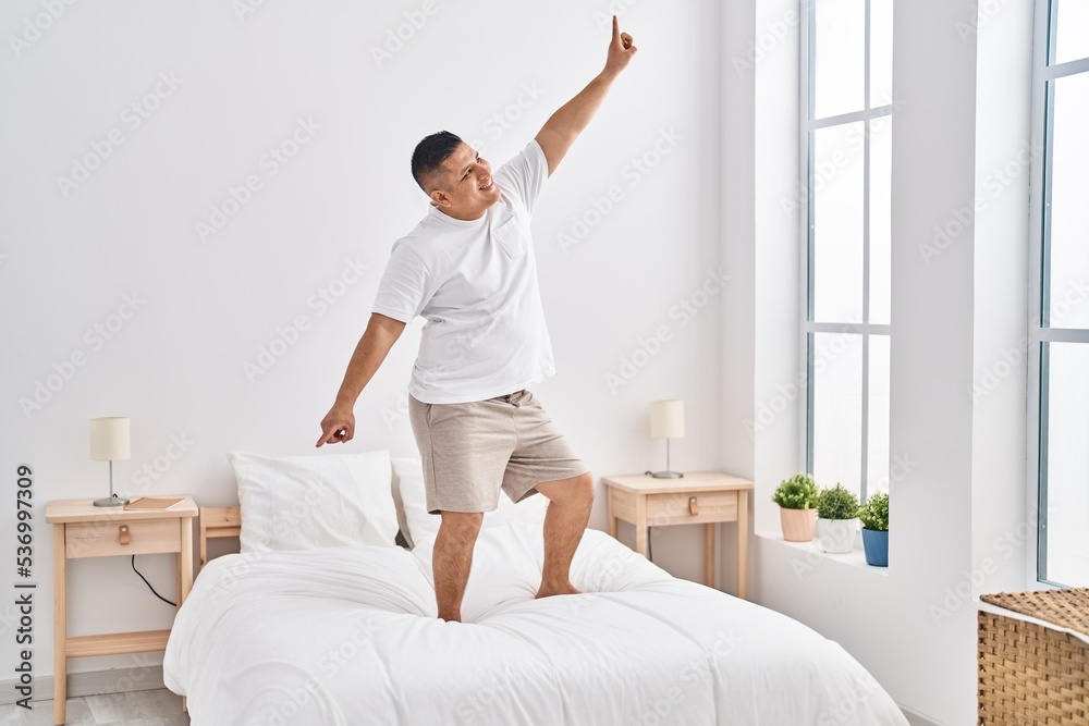 Young latin man smiling confident dancing on bed at bedroom Young latin man smiling confident dancing on bed at bedroom