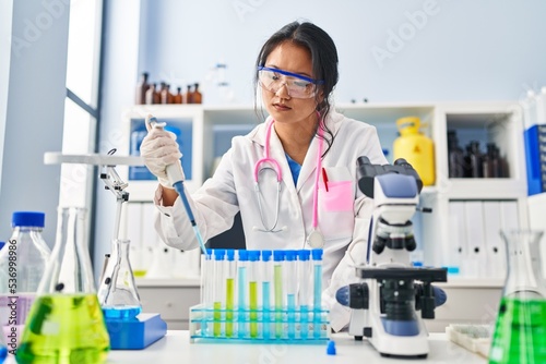 Fototapeta Naklejka Na Ścianę i Meble -  Young chinese woman wearing scientist uniform working at laboratory