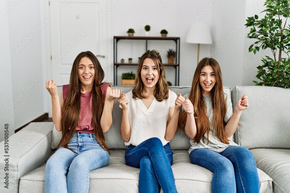 Φωτογραφία Group of three hispanic girls sitting on the sofa at home celebrating surprised and amazed for success with arms raised and open eyes