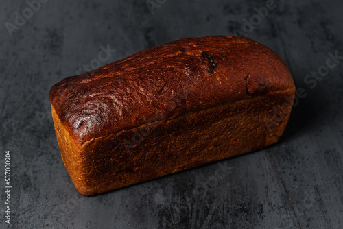 loaf of black bread with prunes on a black background, close view
