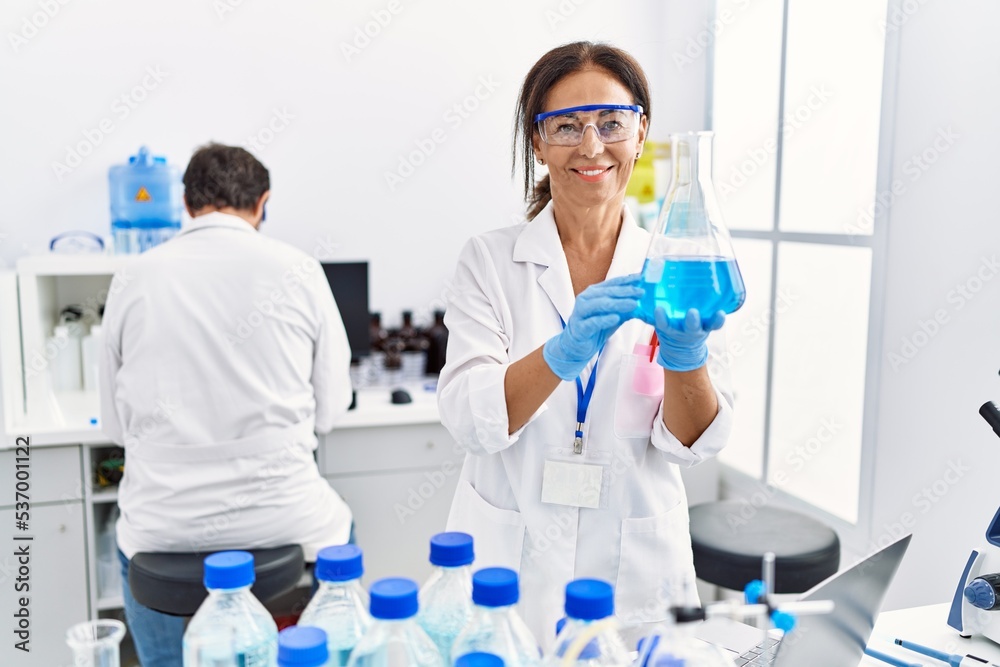 Middle age man and woman partners wearing scientist uniform holding test tube at laboratory Middle age man and woman partners wearing scientist uniform holding test tube at laboratory