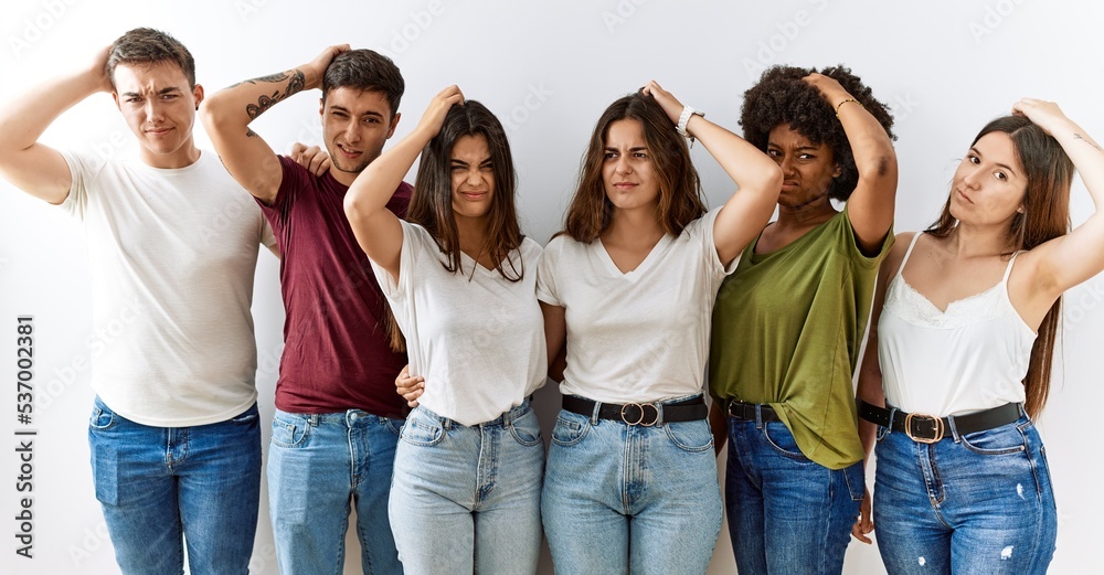 Fototapeta premium Group of young friends standing together over isolated background confuse and wondering about question. uncertain with doubt, thinking with hand on head. pensive concept.