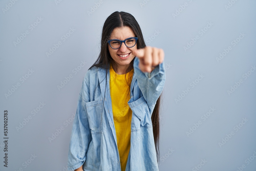 Young hispanic woman standing over blue background pointing displeased and frustrated to the camera, angry and furious with you Young hispanic woman standing over blue background pointing displeased and frustrated to the camera, angry and furious with you