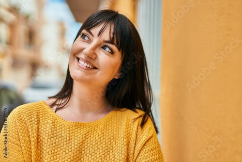 Young brunette woman smiling happy leaning on the wall