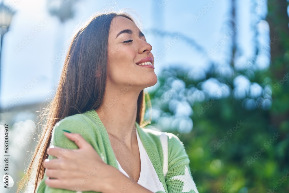 Young beautiful hispanic woman smiling confident hugging himself at park Young beautiful hispanic woman smiling confident hugging himself at park