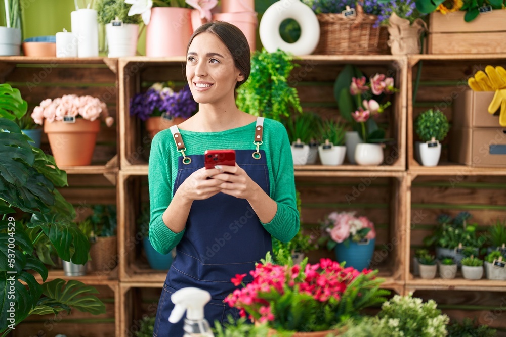 Young beautiful hispanic woman florist smiling confident using smartphone at flower shop