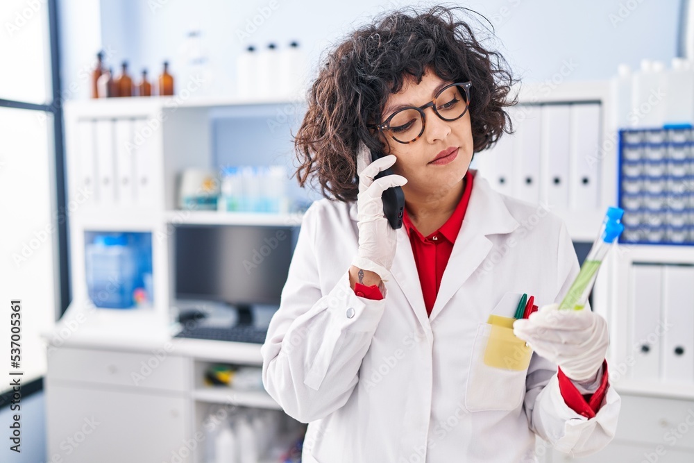 Young beautiful hispanic woman scientist talking on smartphone holding test tube at street Young beautiful hispanic woman scientist talking on smartphone holding test tube at street