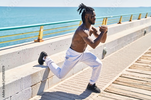 African american woman shirtless training legs exercise at seaside