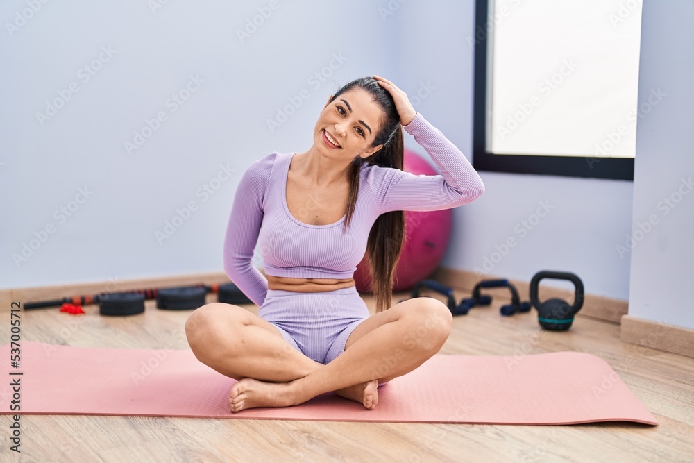 Fototapeta premium Young beautiful hispanic woman smiling confident stretching head at sport center