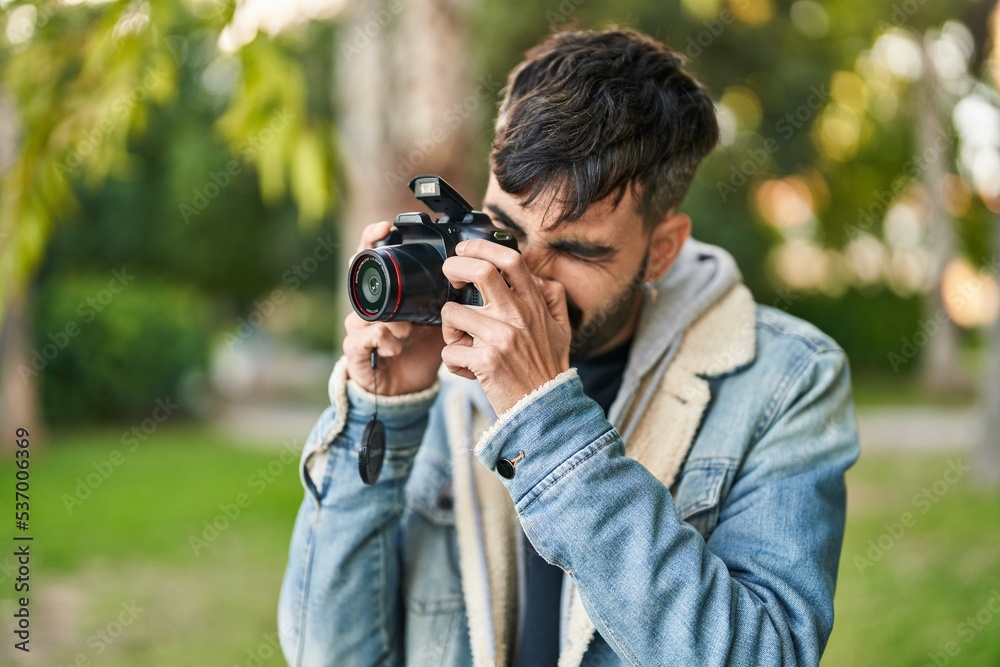 Young hispanic man using professional camera at park Young hispanic man using professional camera at park