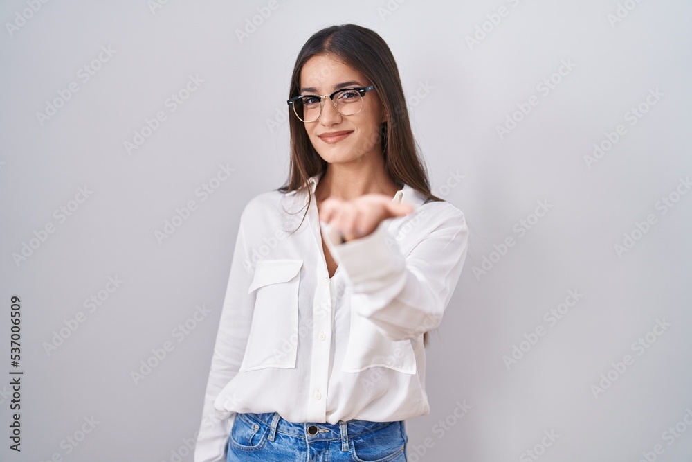 Young brunette woman wearing glasses smiling cheerful offering palm hand giving assistance and acceptance. Young brunette woman wearing glasses smiling cheerful offering palm hand giving assistance and acceptance.