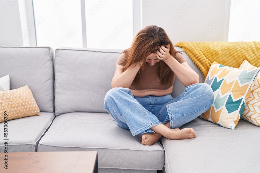 Young woman stressed sitting on sofa at home Young woman stressed sitting on sofa at home