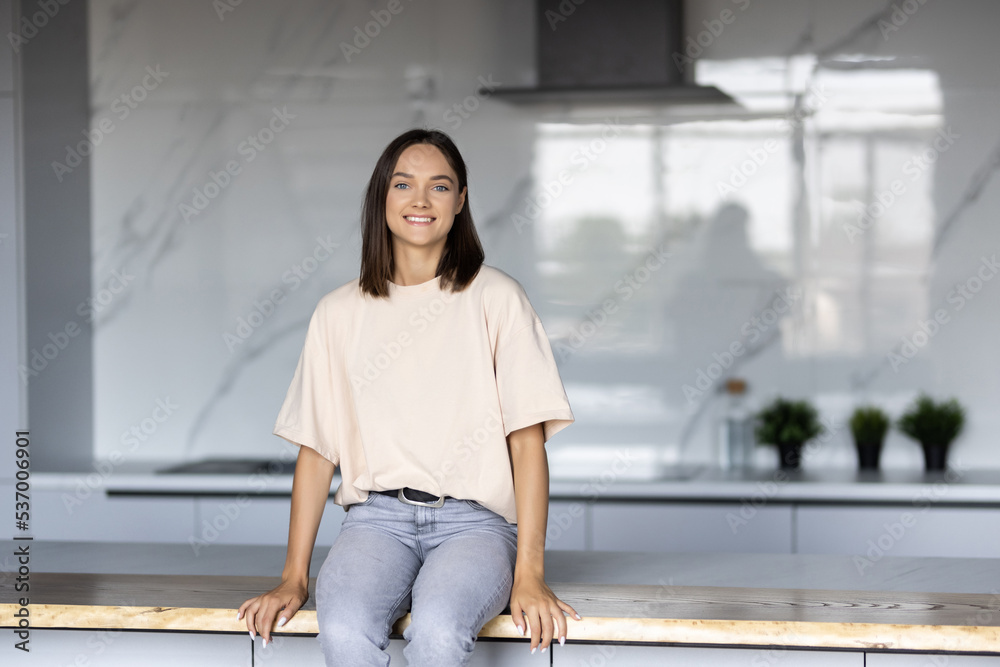 Young beautiful woman stands near table on kitchen at home. Young beautiful woman stands near table on kitchen at home.