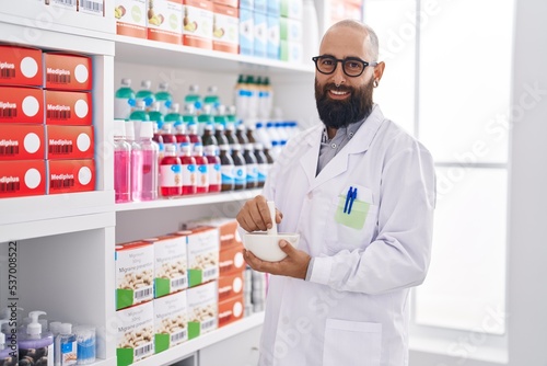 Young bald man pharmacist smiling confident make mixture at pharmacy