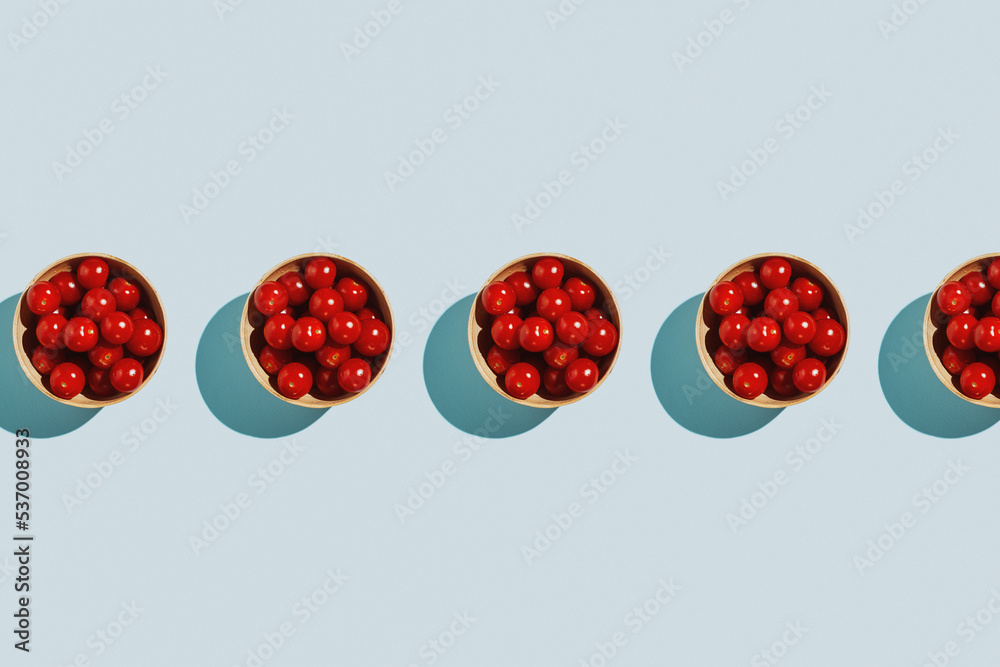 Fototapeta premium Cherry tomatoes in bamboo bowl on pastel blue