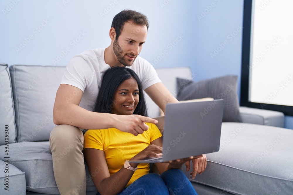 Man and woman interracial couple using laptop at home Man and woman interracial couple using laptop at home