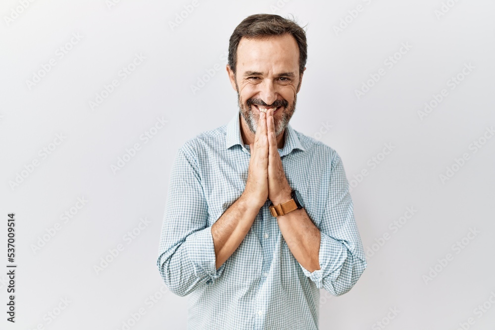 Middle age hispanic man with beard standing over isolated background praying with hands together asking for forgiveness smiling confident. Middle age hispanic man with beard standing over isolated background praying with hands together asking for forgiveness smiling confident.