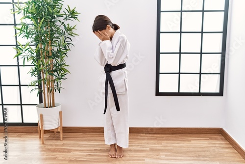 Young hispanic girl wearing karate kimono and black belt with sad expression covering face with hands while crying. depression concept. © Krakenimages.com