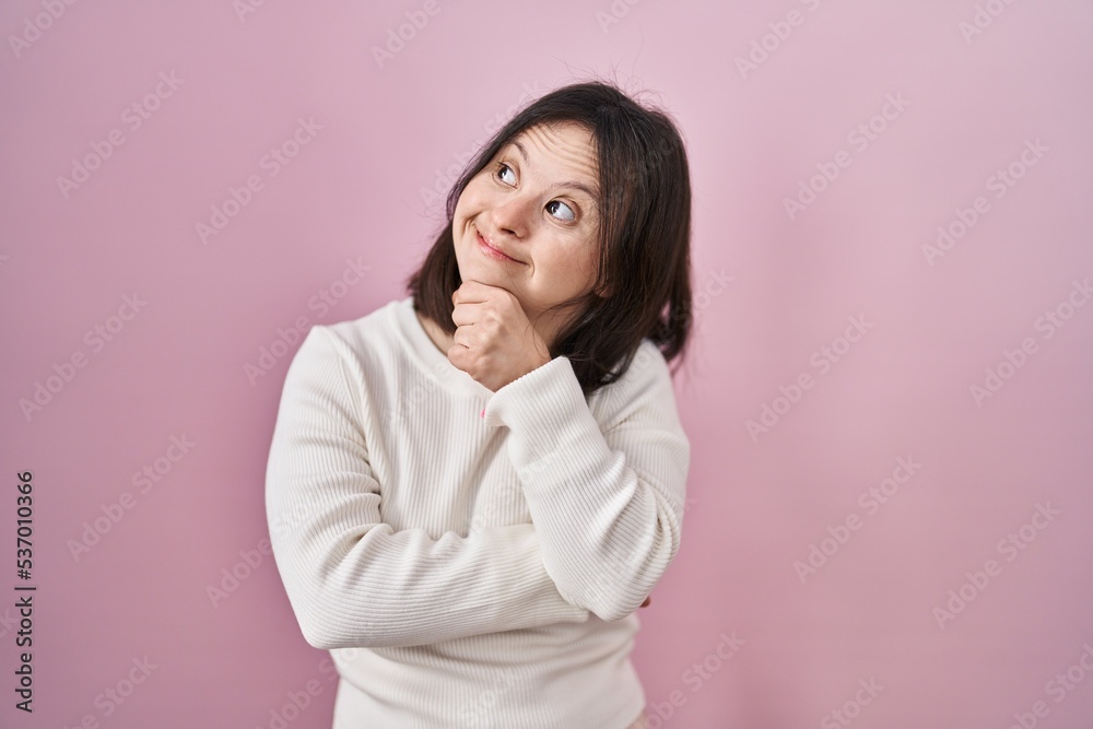 Woman with down syndrome standing over pink background thinking worried about a question, concerned and nervous with hand on chin Woman with down syndrome standing over pink background thinking worried about a question, concerned and nervous with hand on chin