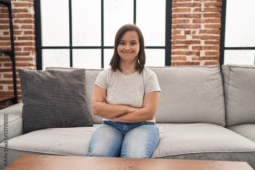 Down syndrome woman sitting on the sofa with arms crossed gesture at home