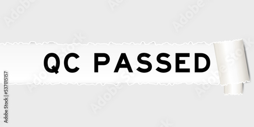 Ripped gray paper background that have word QC (quality control) passed under torn part