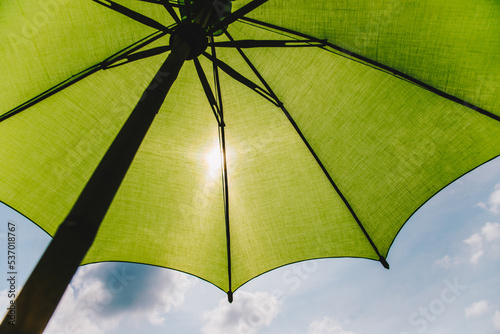 Ant view under Green umbrella with sunlight and blue sky for background concept idea