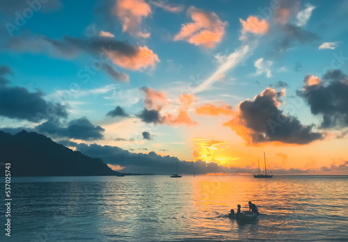 Multi colored tropic sunset over calm sea water. Yacht boats silhouette against blue orange clouds in sky  mountain in background. Beautiful nature landscape. Travel  tourism  holiday destination