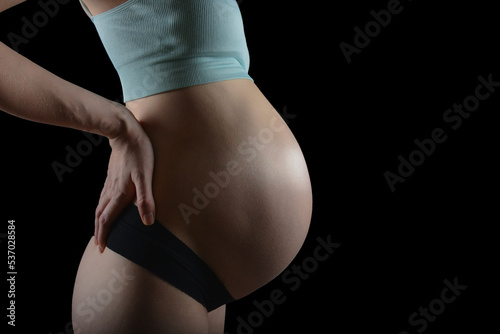 Big pregnant belly, A beautiful pregnat woman on black background, Motherhood. Fashion photo for pregnancy