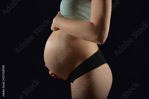 Fashion photo for pregnancy, A beautiful pregnat woman on black background, Motherhood, Big pregnant belly. photo