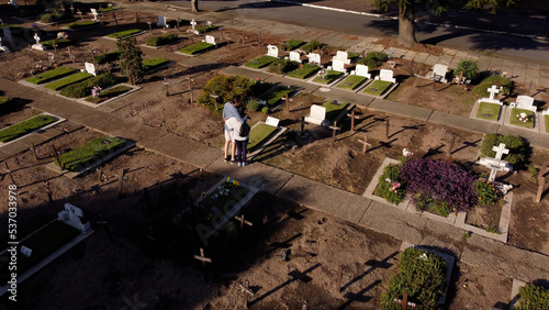 Couple in remembrance of their loved ones, walking through the cemetery. Aerial. Argentina.